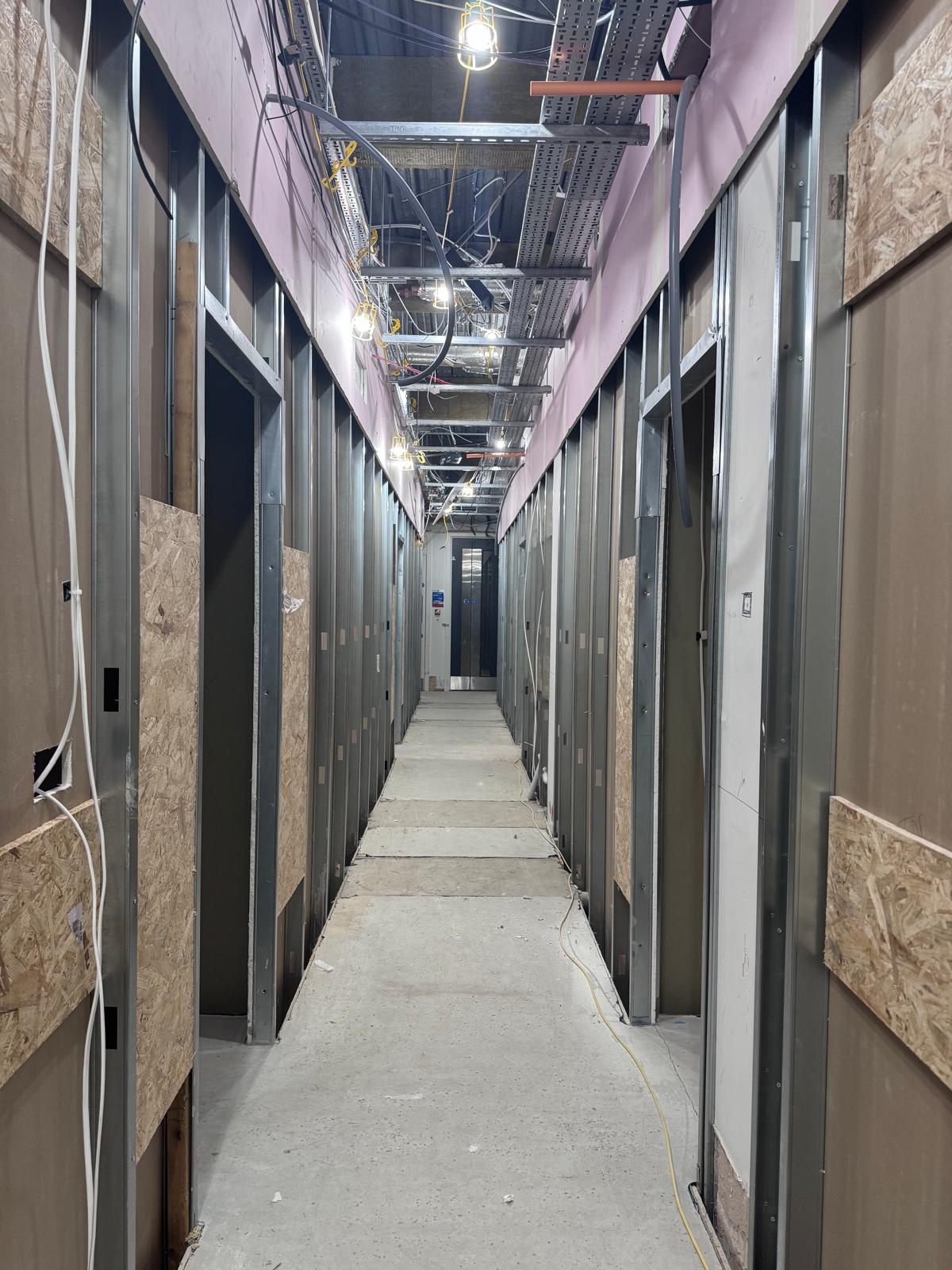 Metal stud partitions and door openings along a corridor during construction